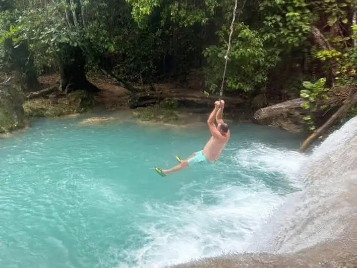 A guest swinging on a rope into the Blue Hole's turquoise water