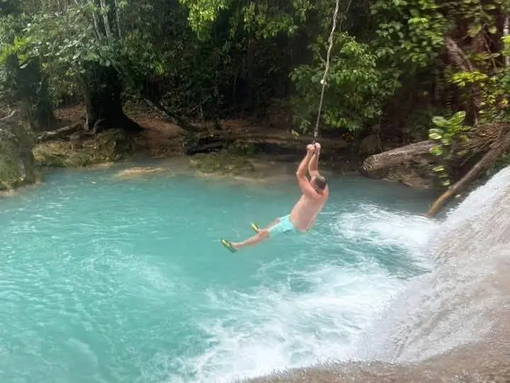 A guest swinging on a rope into the Blue Hole's turquoise water