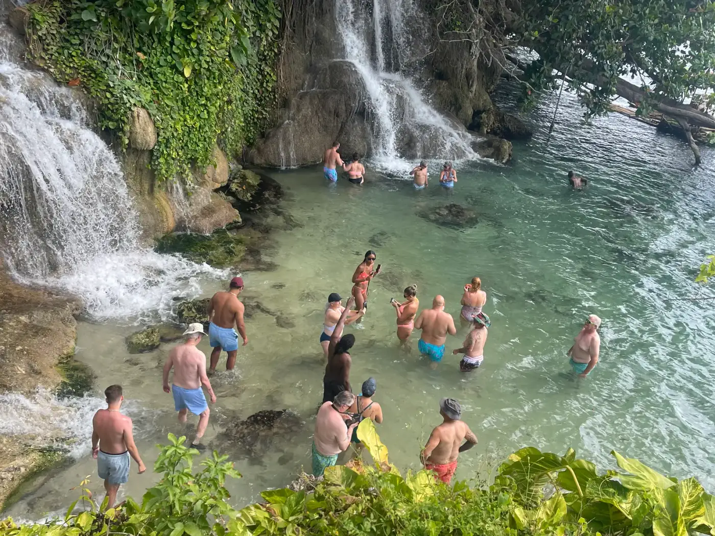 Guests swimming and taking photos at the base of Hidden Falls